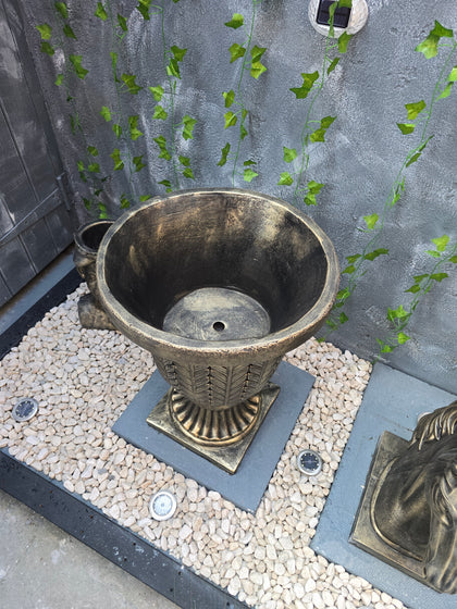 Bronze outdoor lamp on a stone patio with greenery
