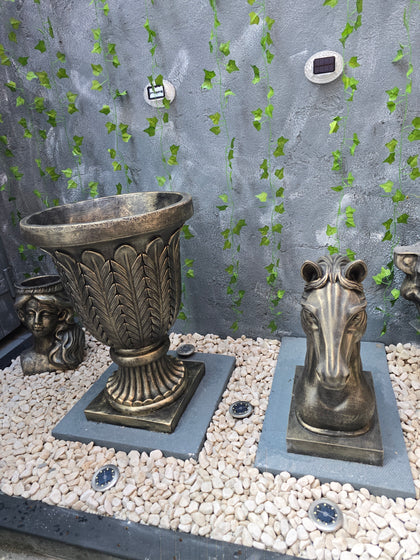 Decorative metal pedestal on a pebble and stone surface